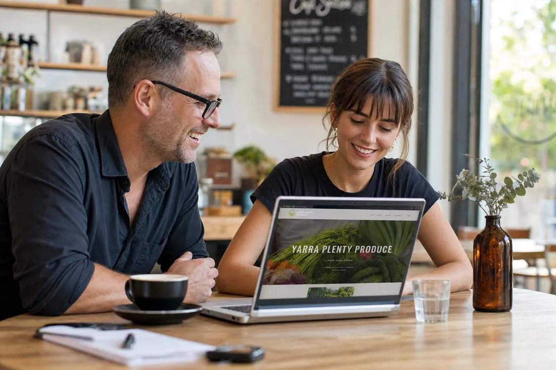 A web designer and a local business owner reviewing a website together at a cafe table